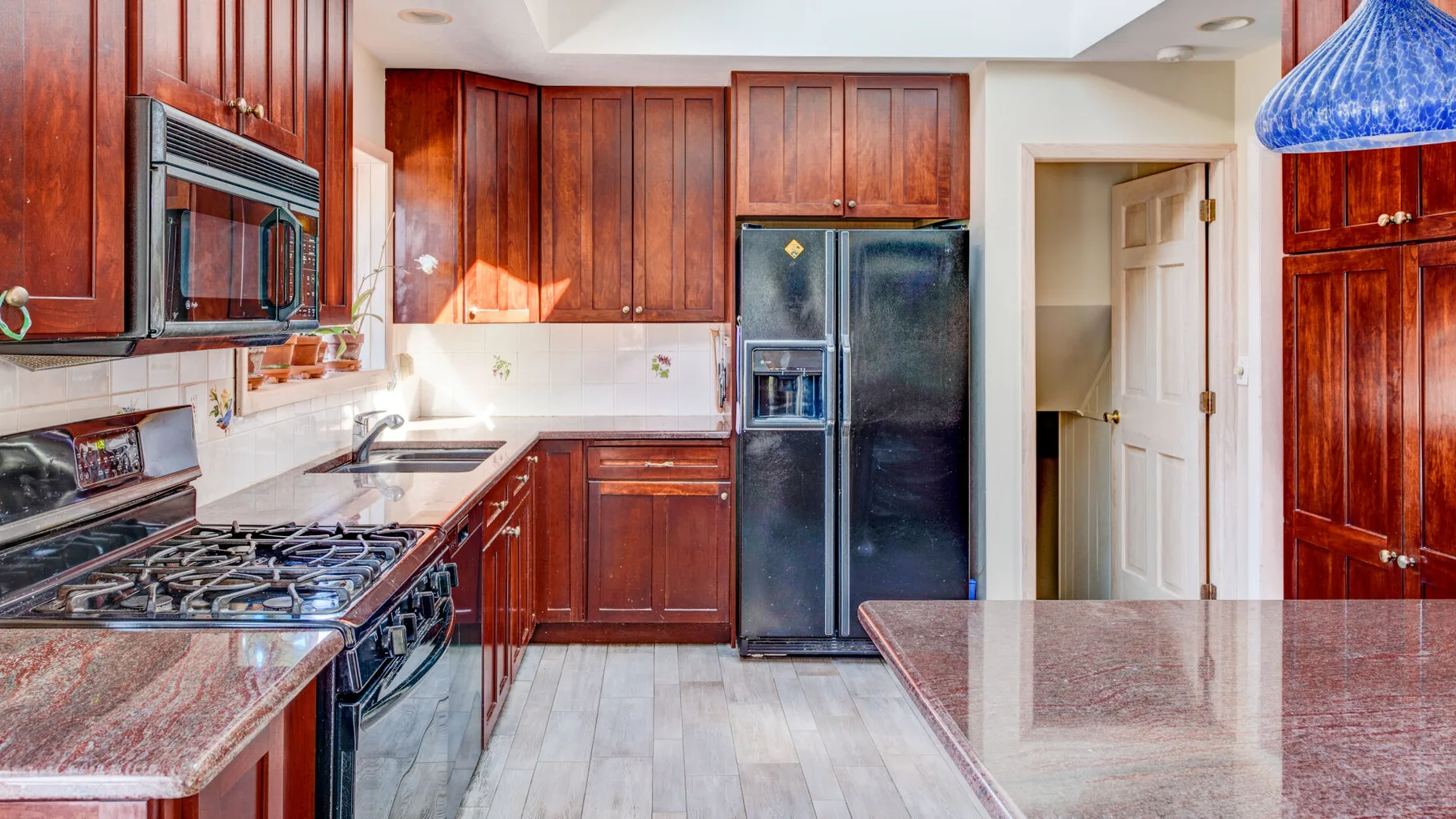 Una cocina con gabinetes de madera oscura, una estufa de gas y un refrigerador.