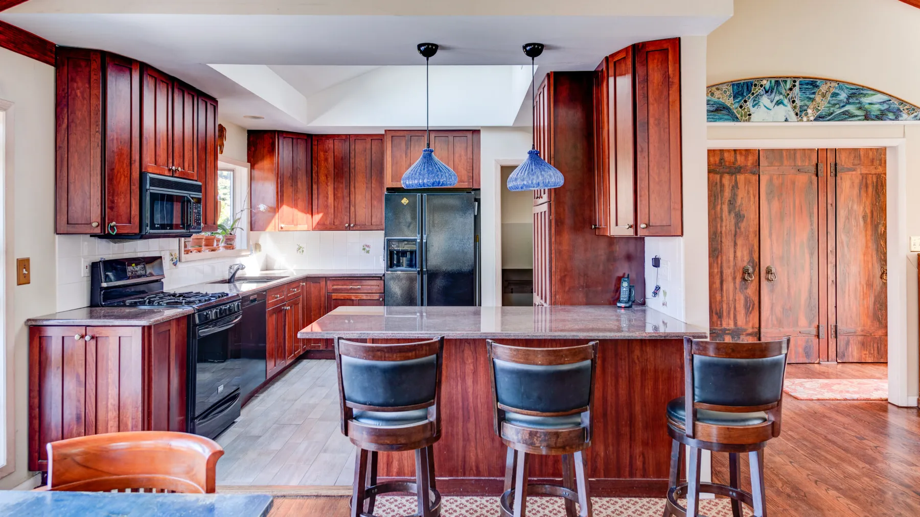 Una cocina con gabinetes de madera oscura, una isla central y asientos de barra.