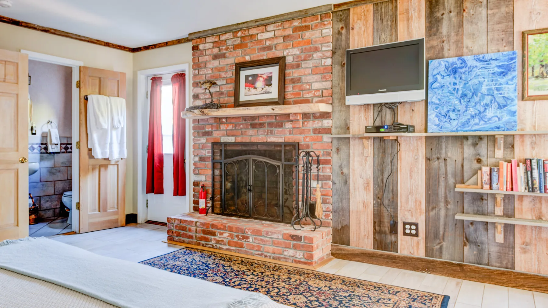 Una sala rústica con una chimenea de ladrillo y un televisor en la pared.