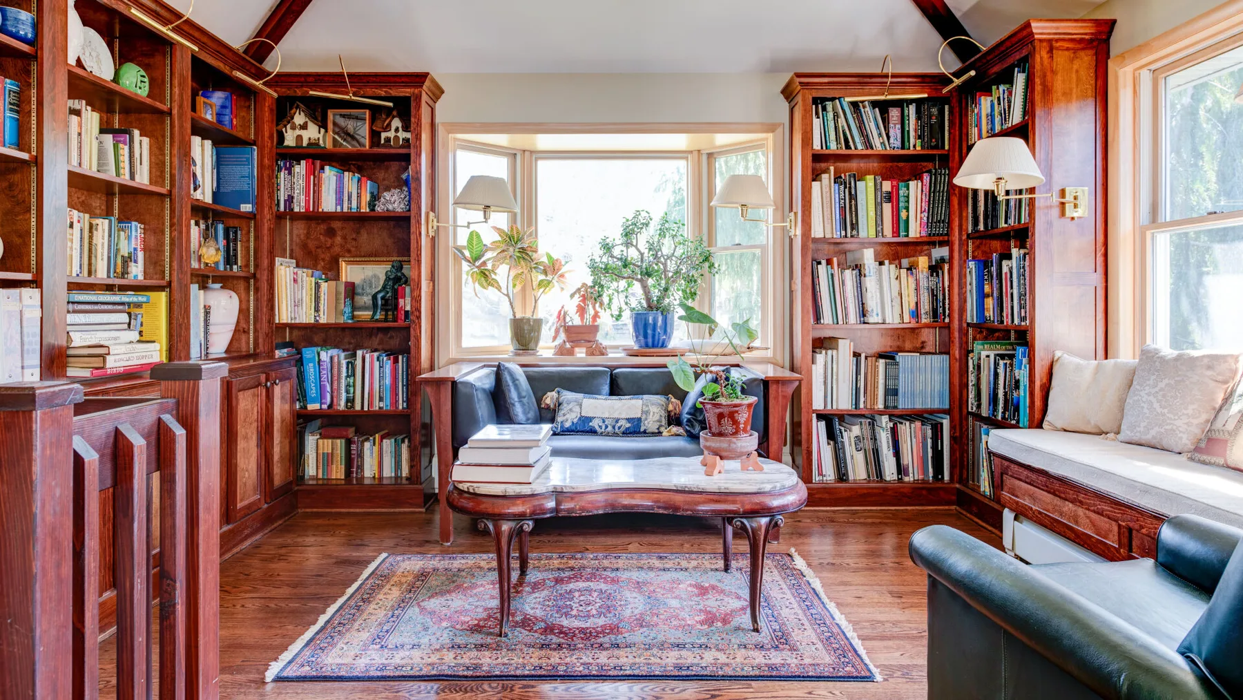 Una sala luminosa con estanterías, un sofá y una mesa de centro.