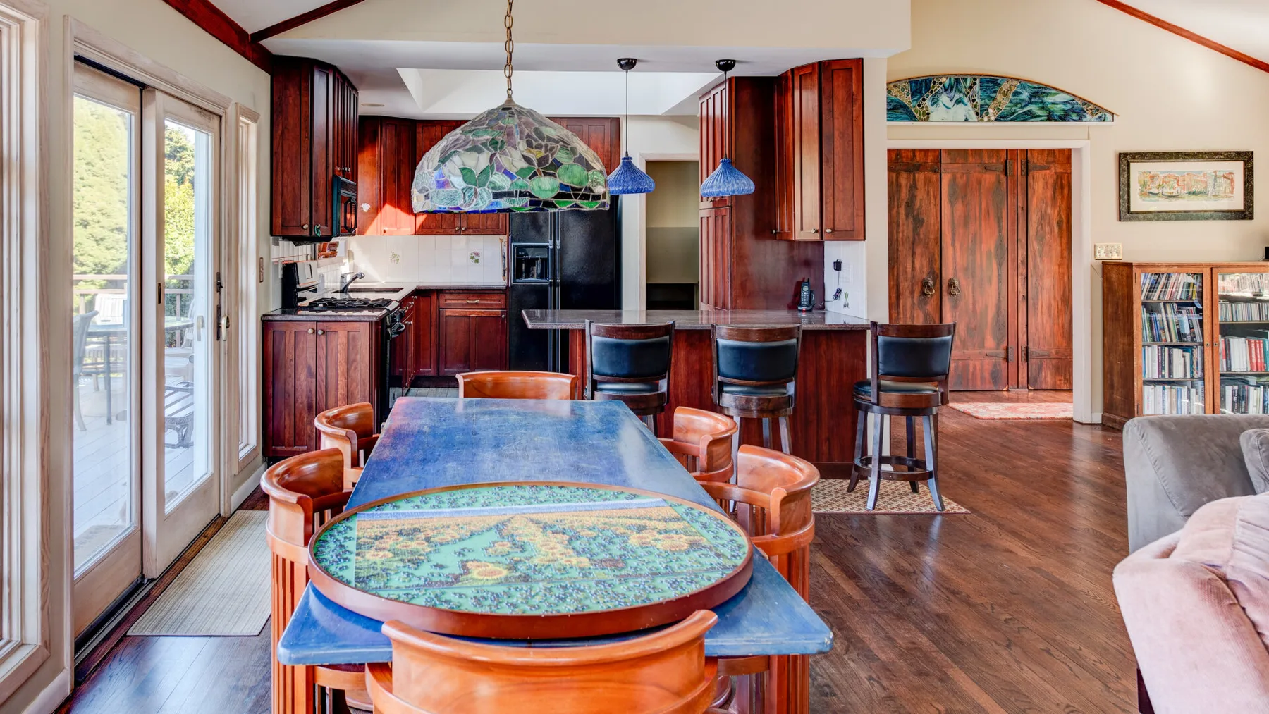 Una cocina y comedor coloridos con una mesa larga y armarios de madera.