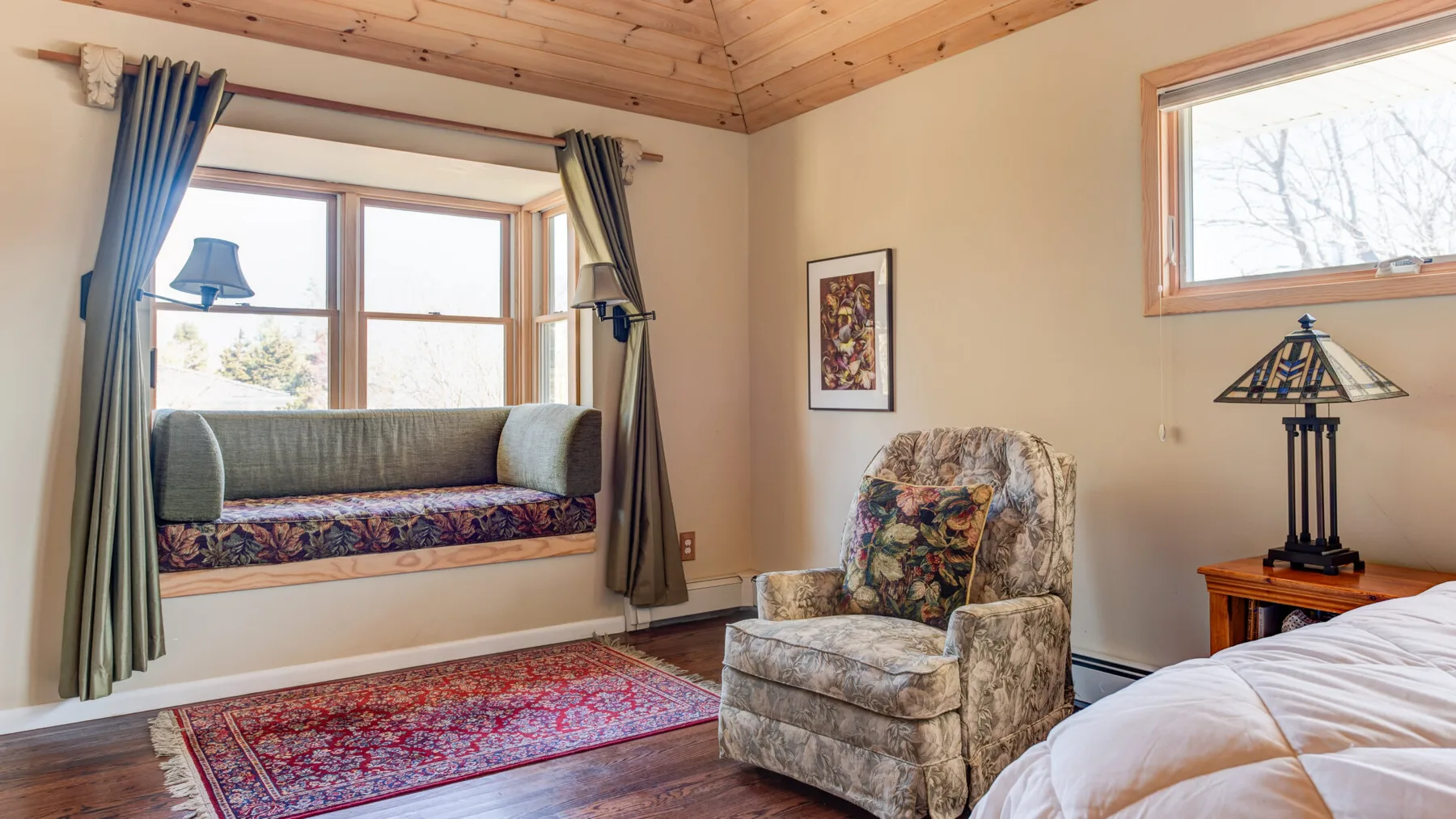 Una zona de descanso en un dormitorio, con un sillón junto a una ventana grande.