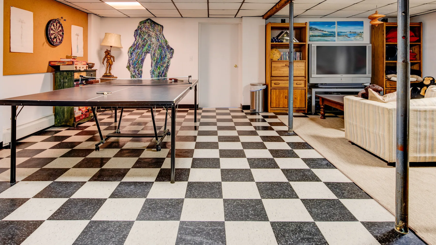 Una sala de recreación con mesa de ping-pong, televisor y asientos.