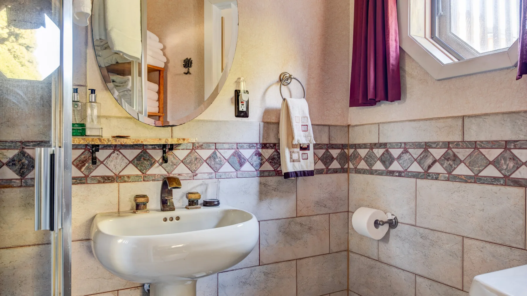 Un baño con un lavabo de pared y una ventana con cortina.