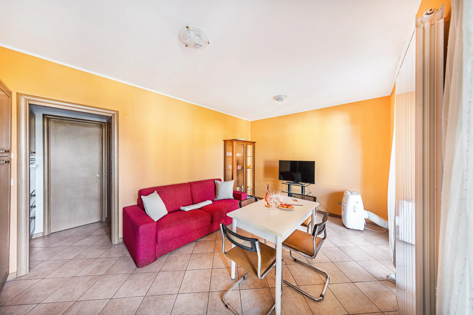 A bright living room with red seating and a dining table.
