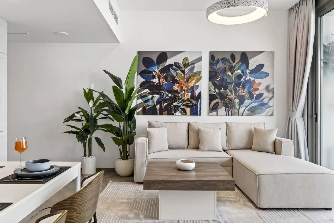 Una sala luminosa con un sofá seccional y cuadros botánicos.