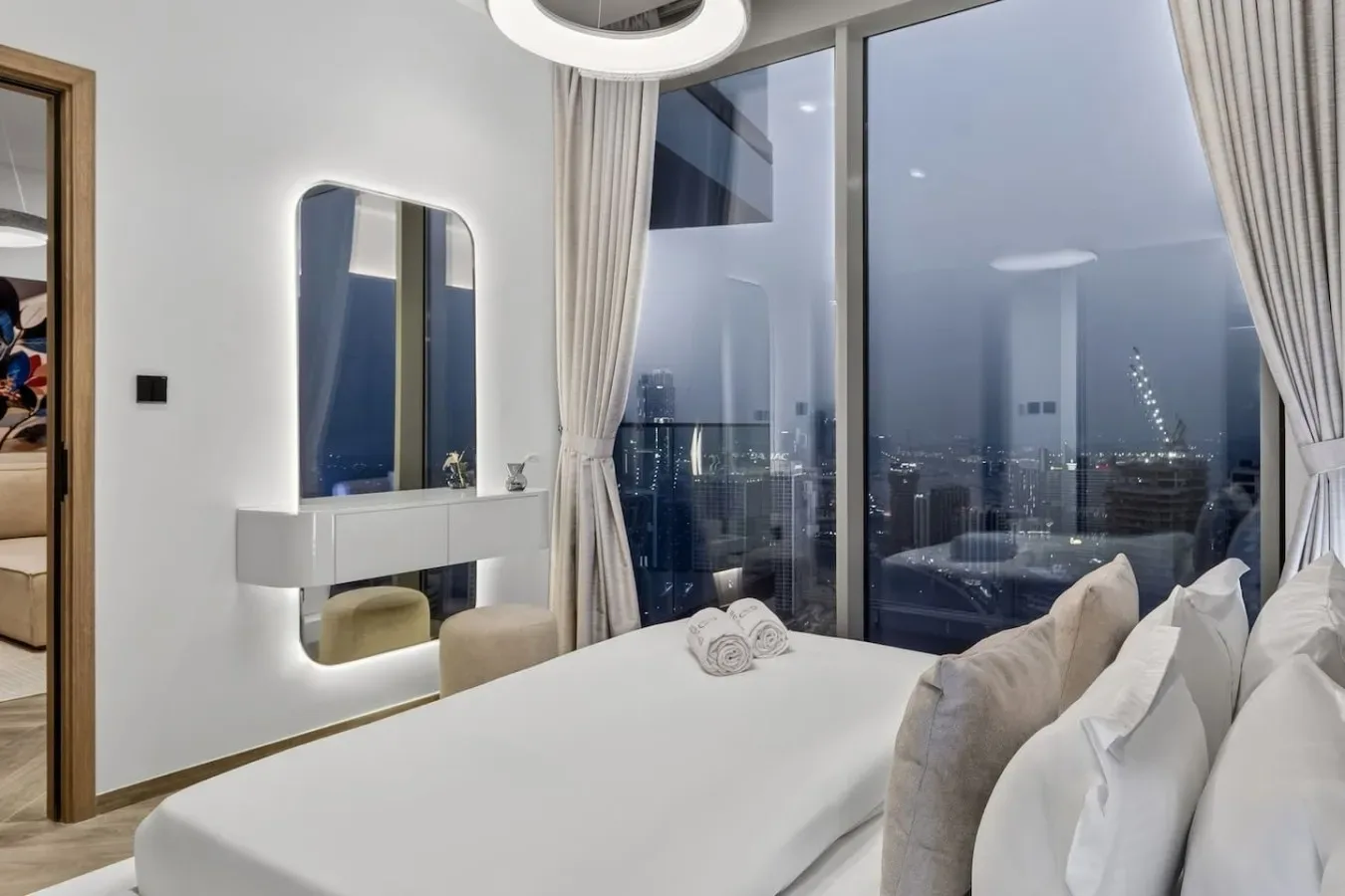 Un dormitorio con una cama junto a grandes ventanas con vistas a la ciudad.