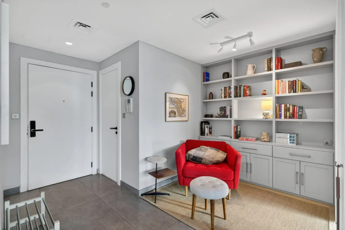 Sala de estar con estanterías empotradas y un sillón rojo.