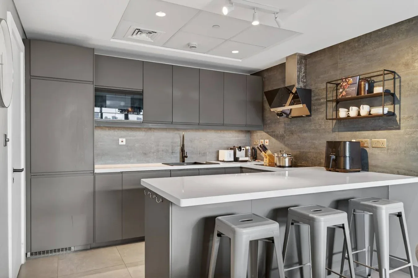 Cocina moderna con armarios grises e isla central con asientos.