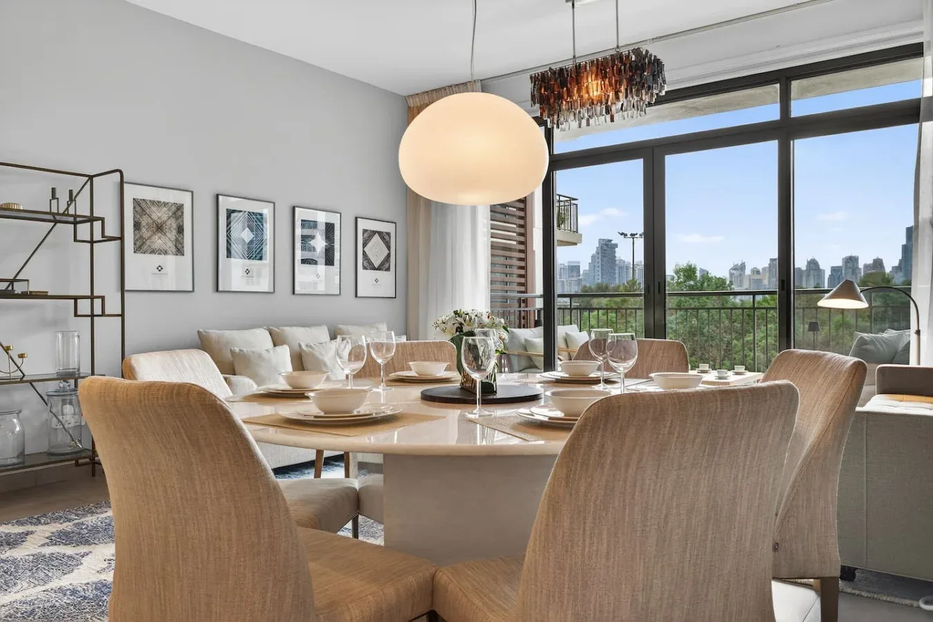 Comedor con la mesa puesta junto a grandes ventanales con vistas a la ciudad.