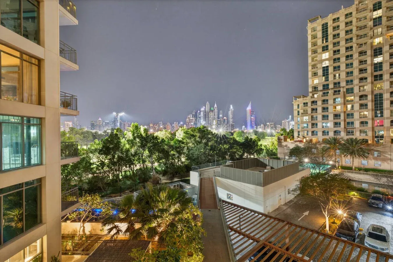 Una vista nocturna de la ciudad se extiende sobre jardines entre edificios residenciales.