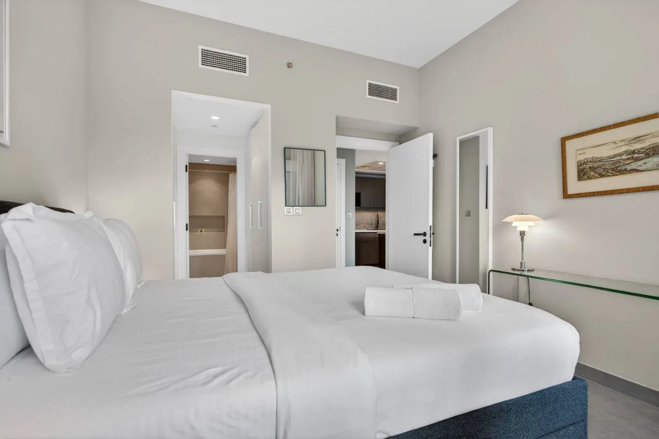 Un dormitorio luminoso con una cama bien tendida y una puerta abierta.