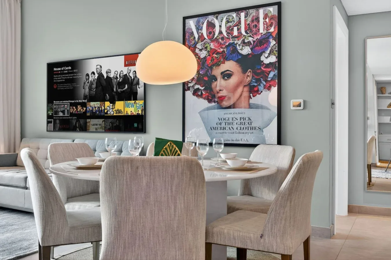 Comedor con asientos tapizados, una mesa y arte colorido en la pared.