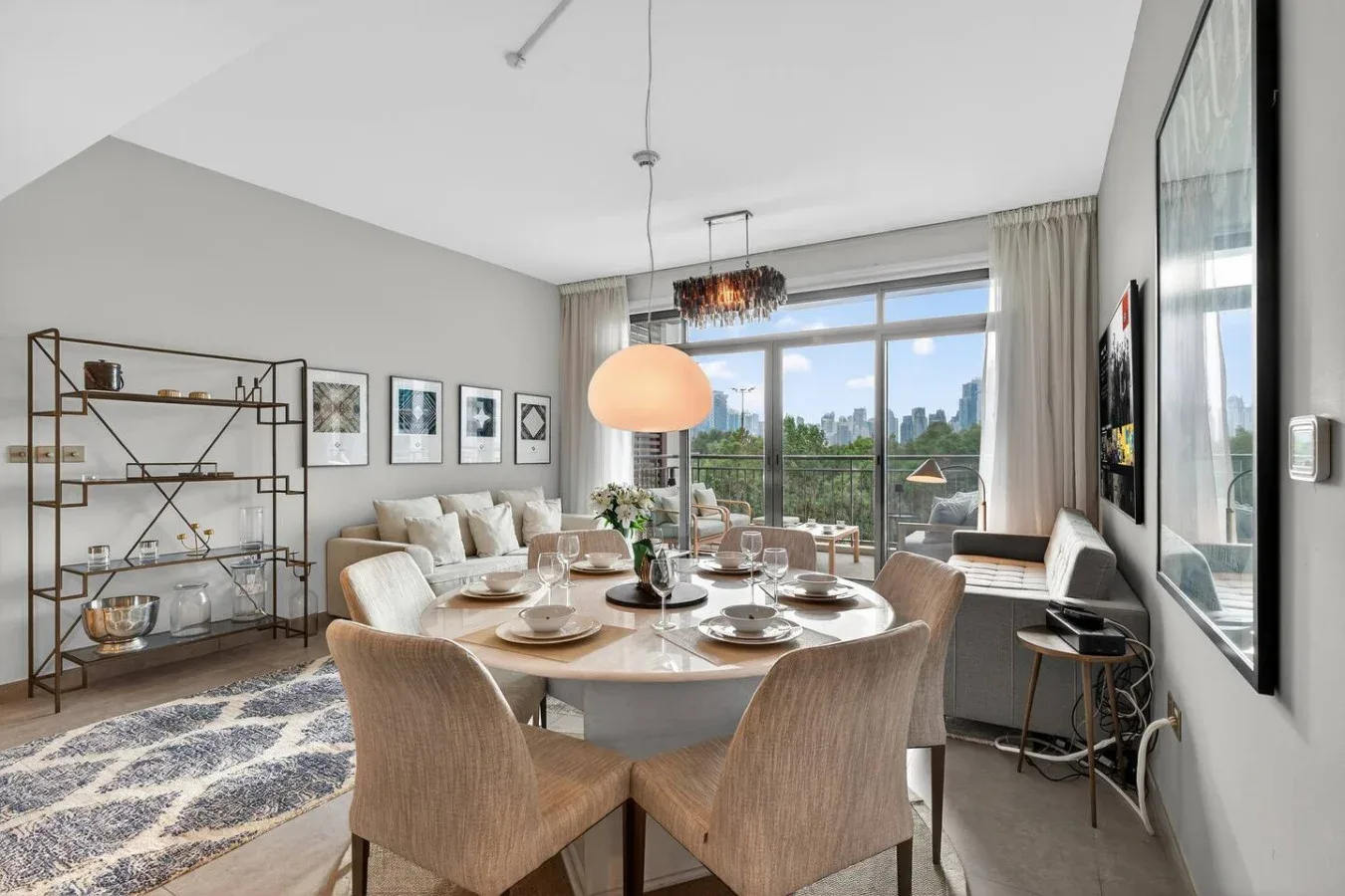 Una luminosa zona de comedor y sala de estar con la mesa puesta y grandes ventanas.