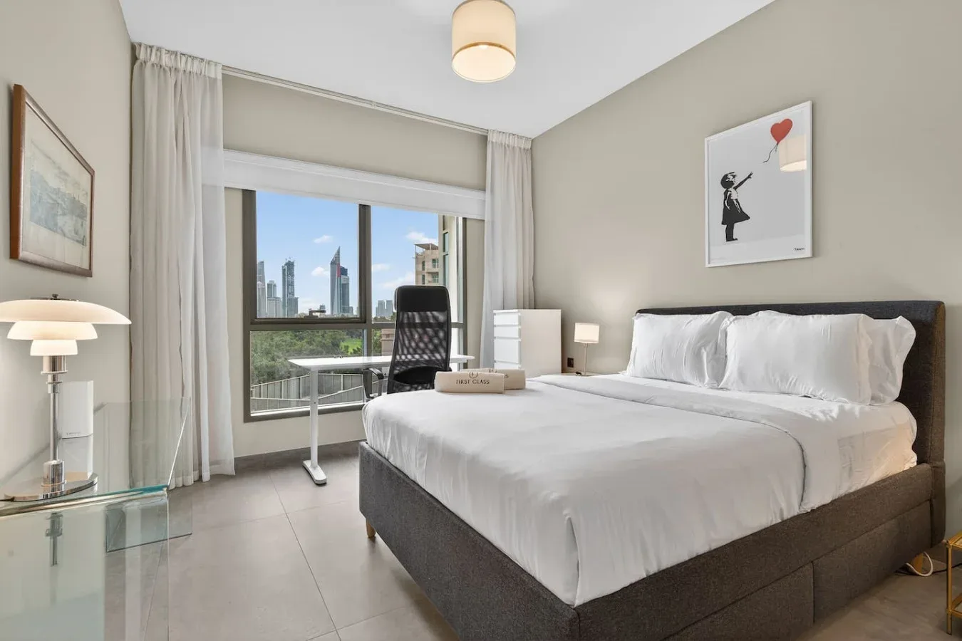 Un dormitorio con una cama tendida y un escritorio junto a la ventana.