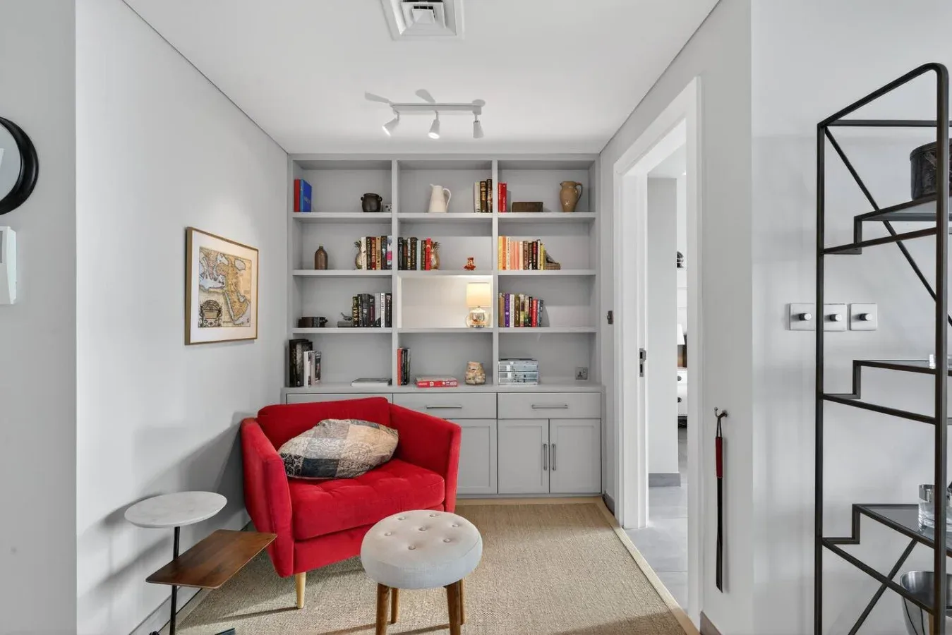 Una sala luminosa tiene un sillón rojo junto a estanterías empotradas.