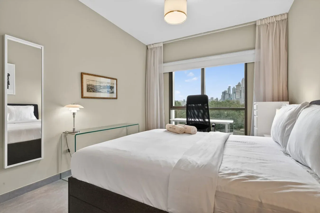 Un dormitorio con una cama grande y una ventana con vistas a edificios cercanos.