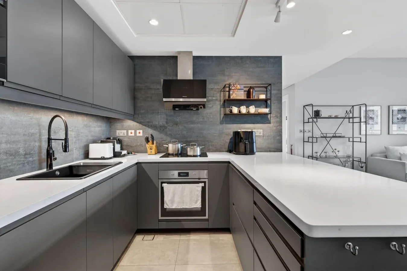 Una cocina moderna con gabinetes grises, una encimera y un horno empotrado.
