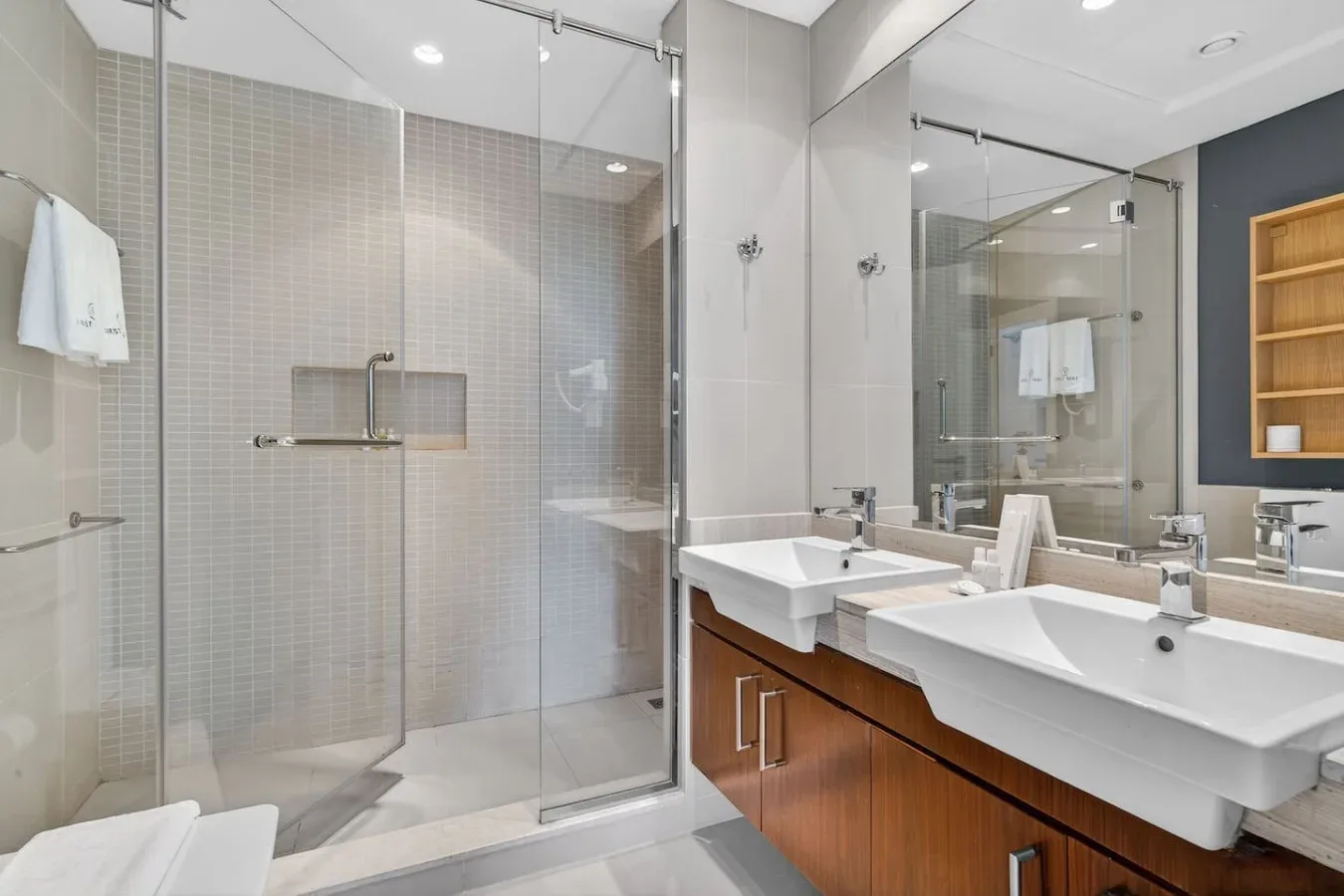 Un baño moderno con ducha de vidrio y lavabos dobles.