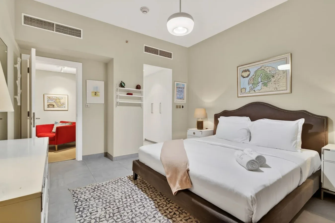 Dormitorio con una cama bien arreglada y una puerta abierta a una zona de estar.