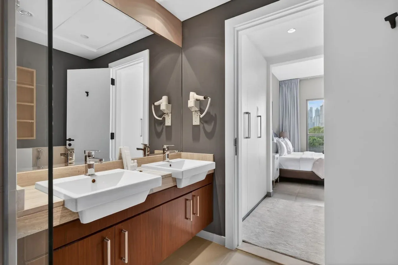 Un mueble de baño con dos lavabos da a un dormitorio.