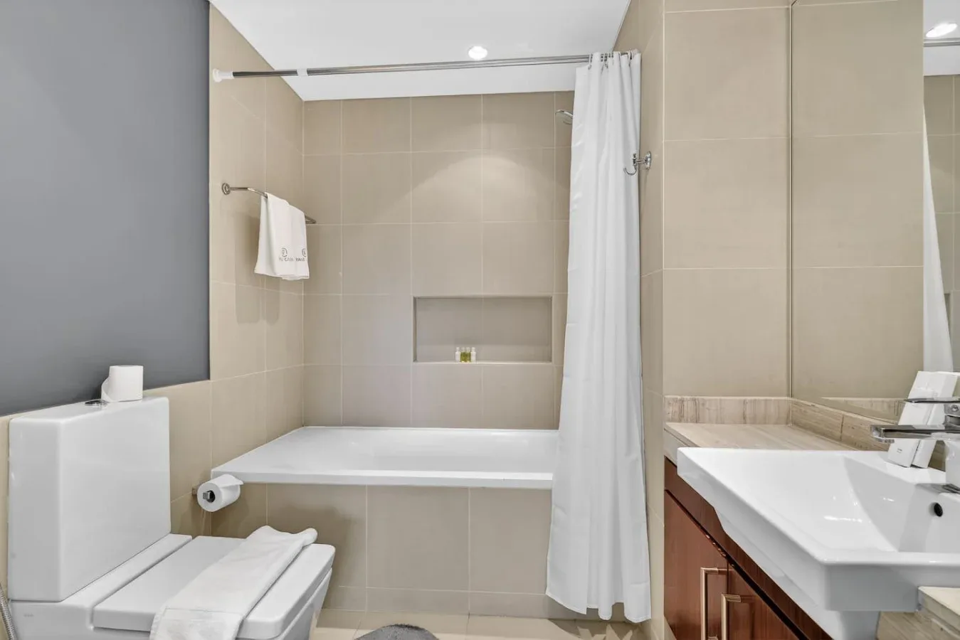 Un baño con bañera, cortina de ducha, inodoro y lavabo.