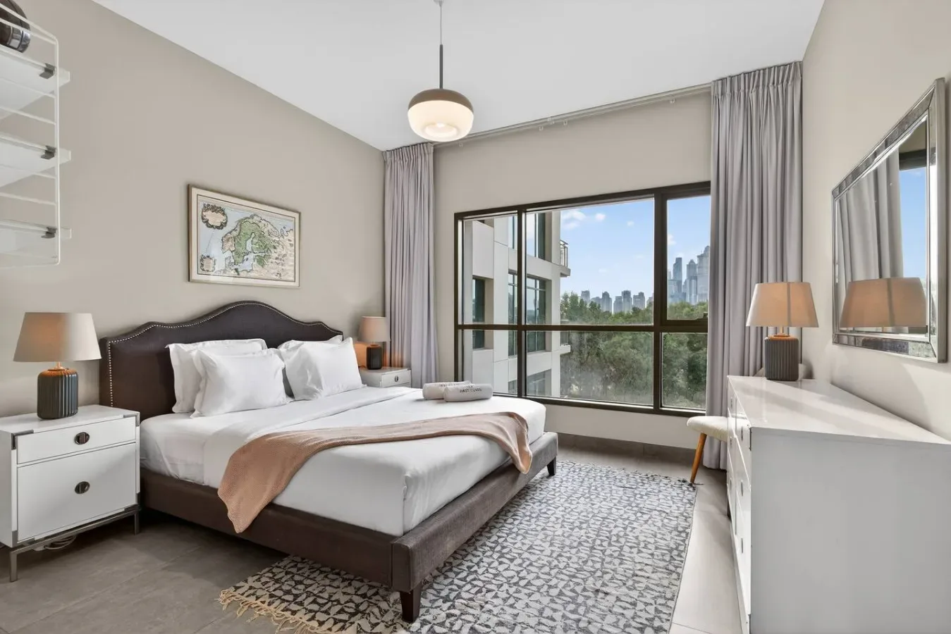 Un dormitorio con una cama junto a una gran ventana con vistas a la ciudad.