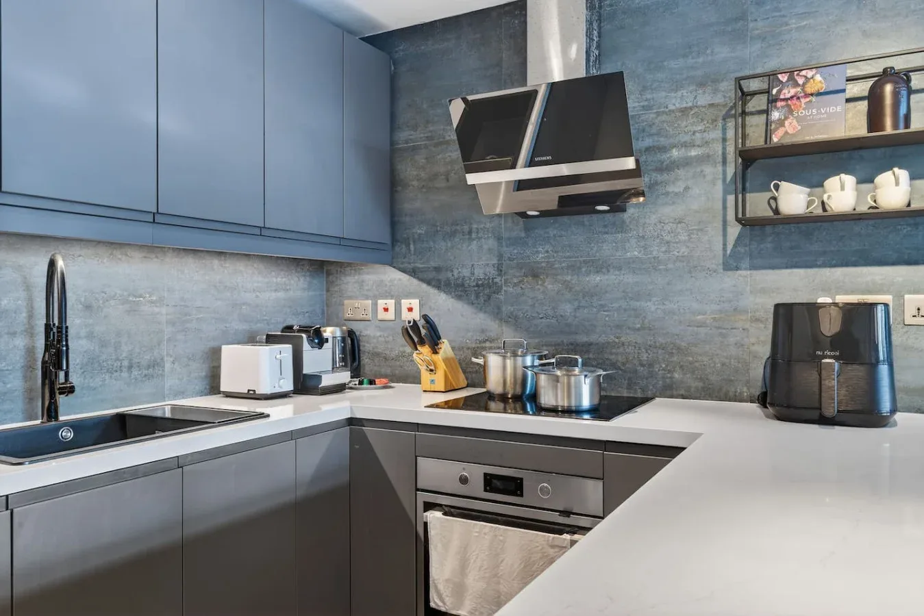 Una cocina moderna con gabinetes grises, una encimera y electrodomésticos de acero inoxidable.