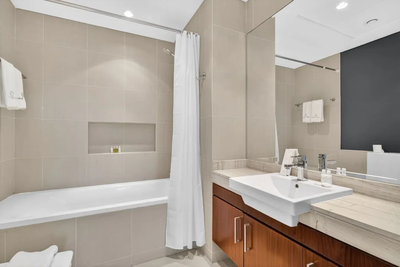 Un baño alicatado con bañera, cortina de ducha y lavabo.