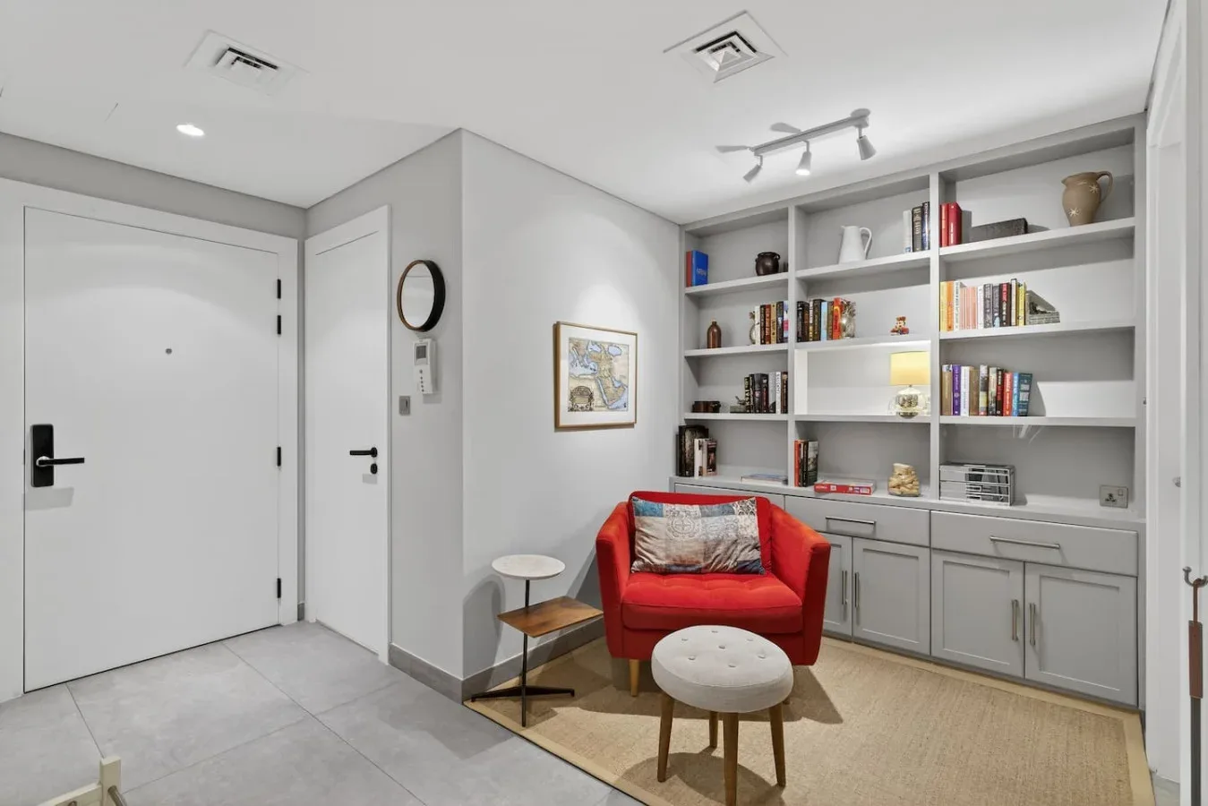 Una sala de estar con estanterías empotradas y un sillón rojo.