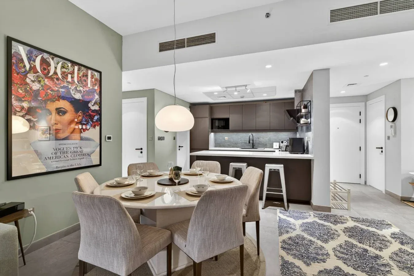 Un comedor con la mesa puesta está junto a una cocina abierta.