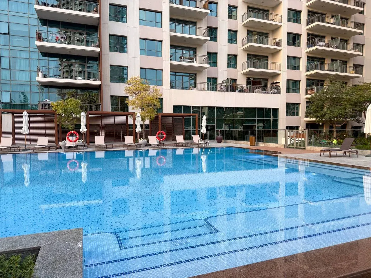 Una piscina frente a un edificio de apartamentos de varias plantas.