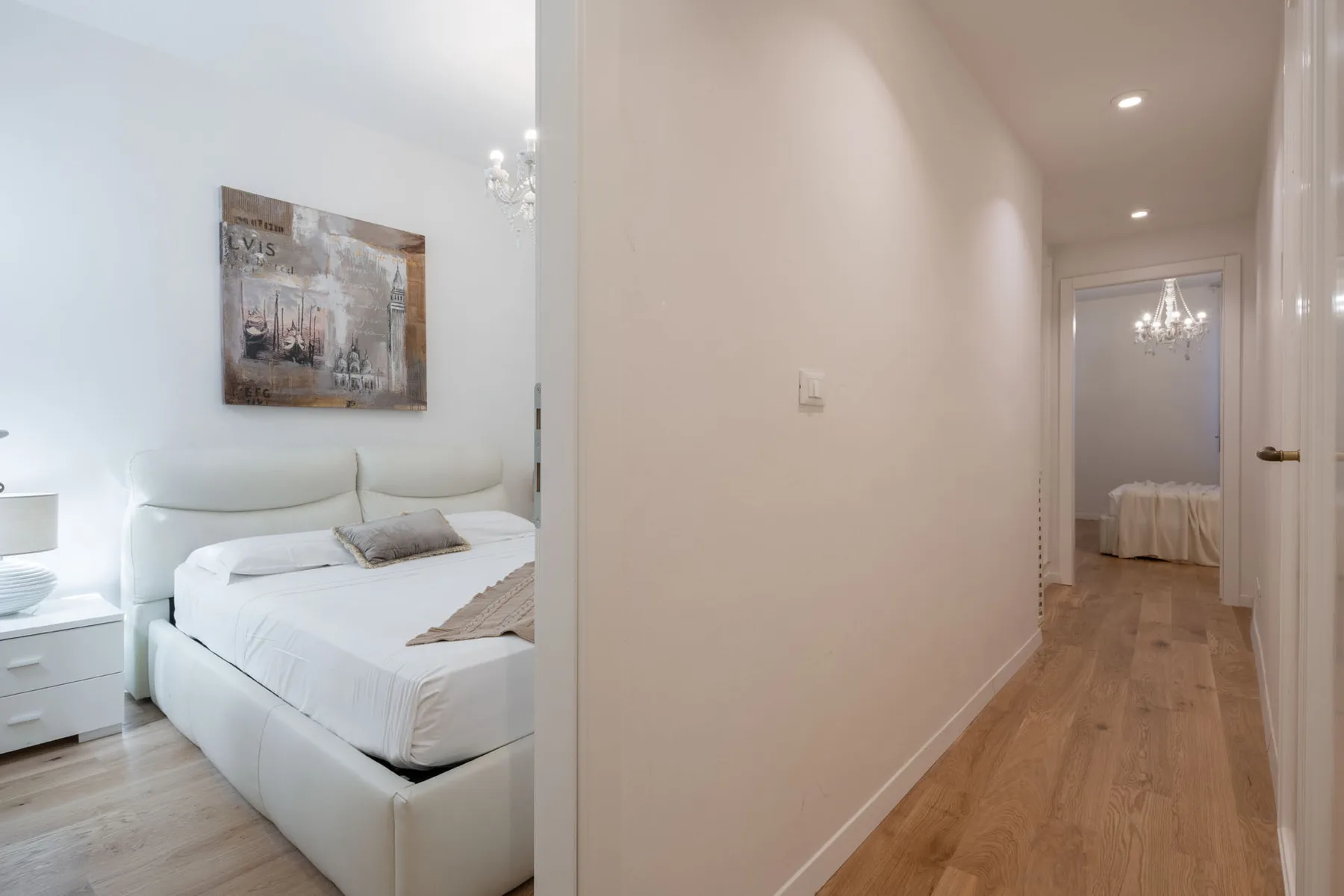 A bright bedroom with a bed and a hallway beside it.