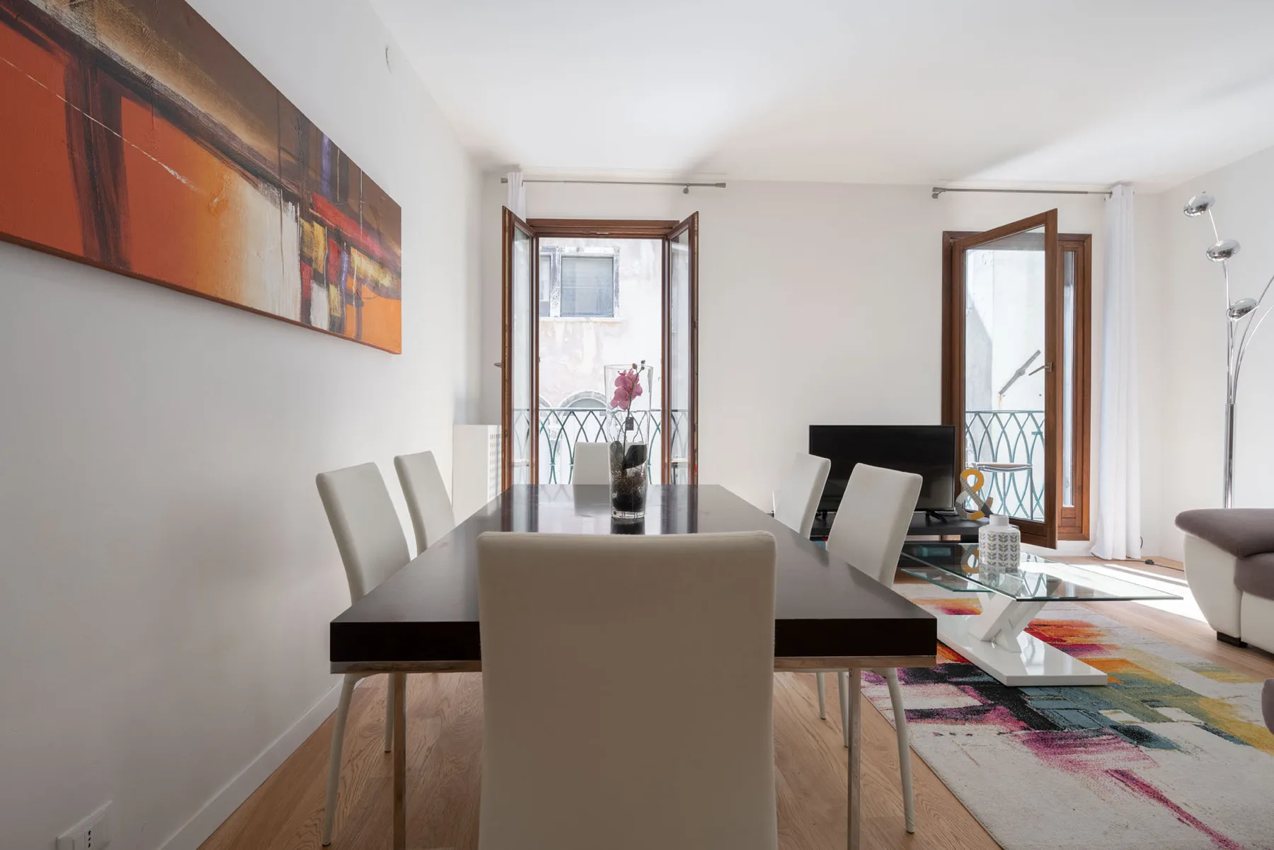 A dining area with a long table and abstract artwork on the wall.