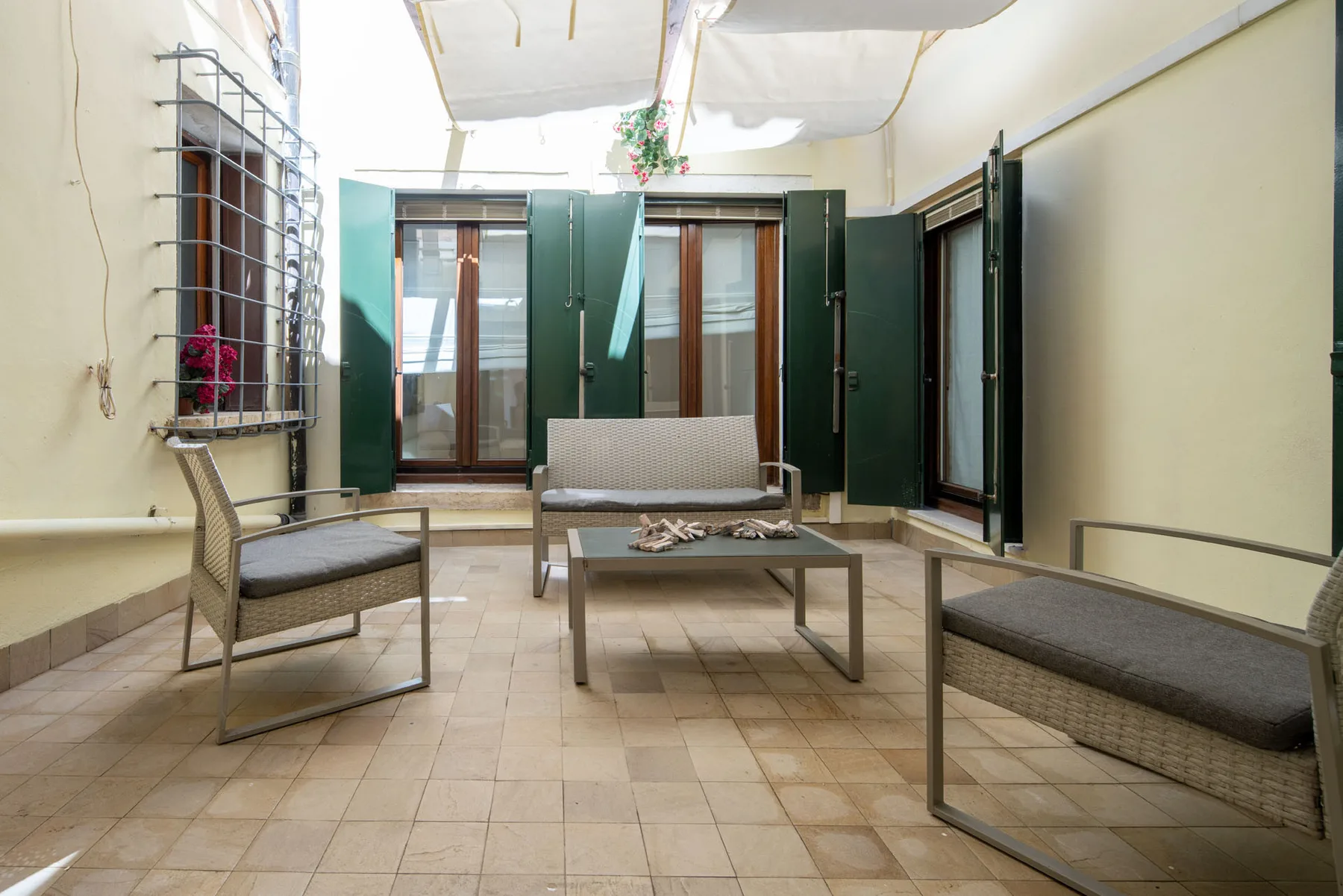 A tiled courtyard seating area with woven chairs and a low table.