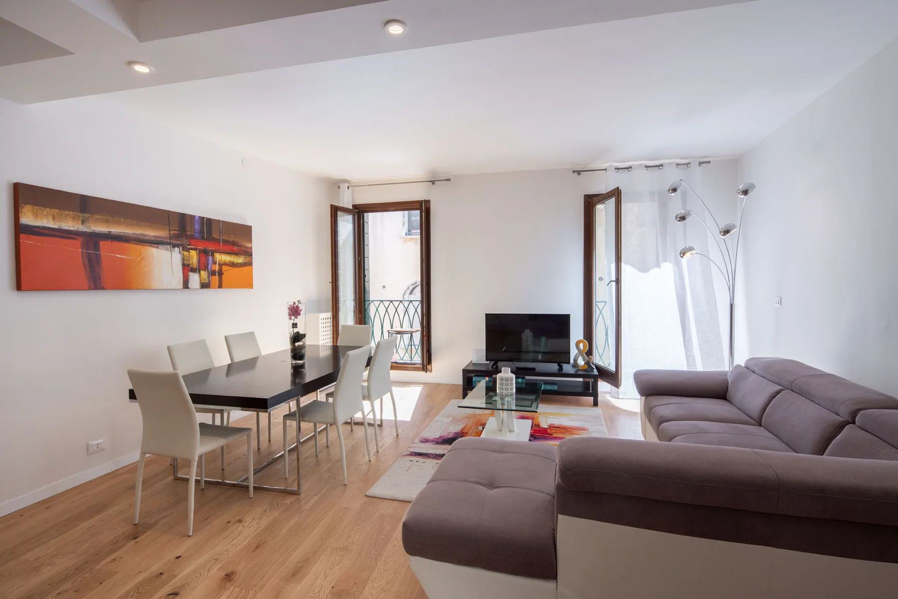 A bright living and dining area with a sectional sofa and dining table.