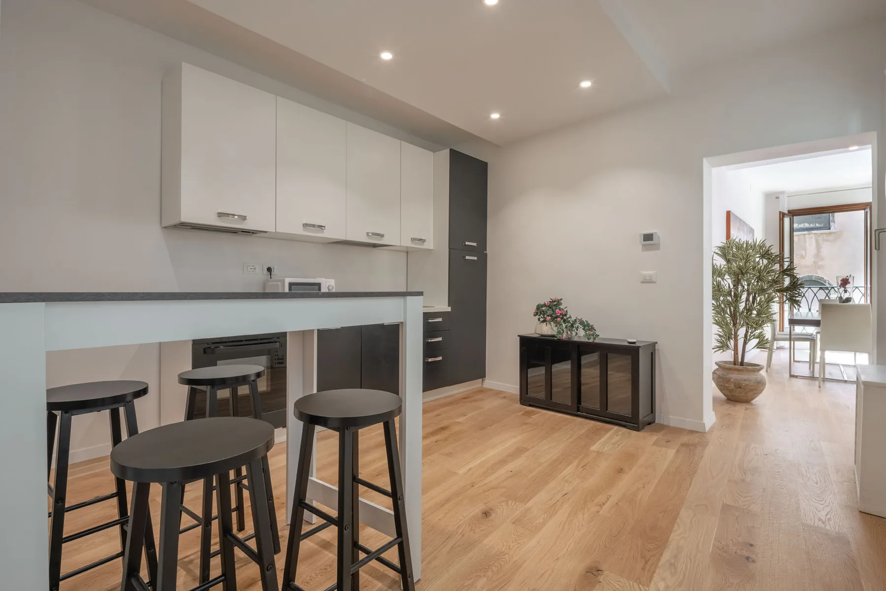A bright kitchen with a breakfast bar and stools beside a dining area.