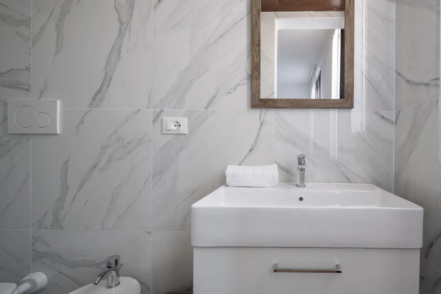A bathroom vanity with a sink and mirror against a tiled wall.