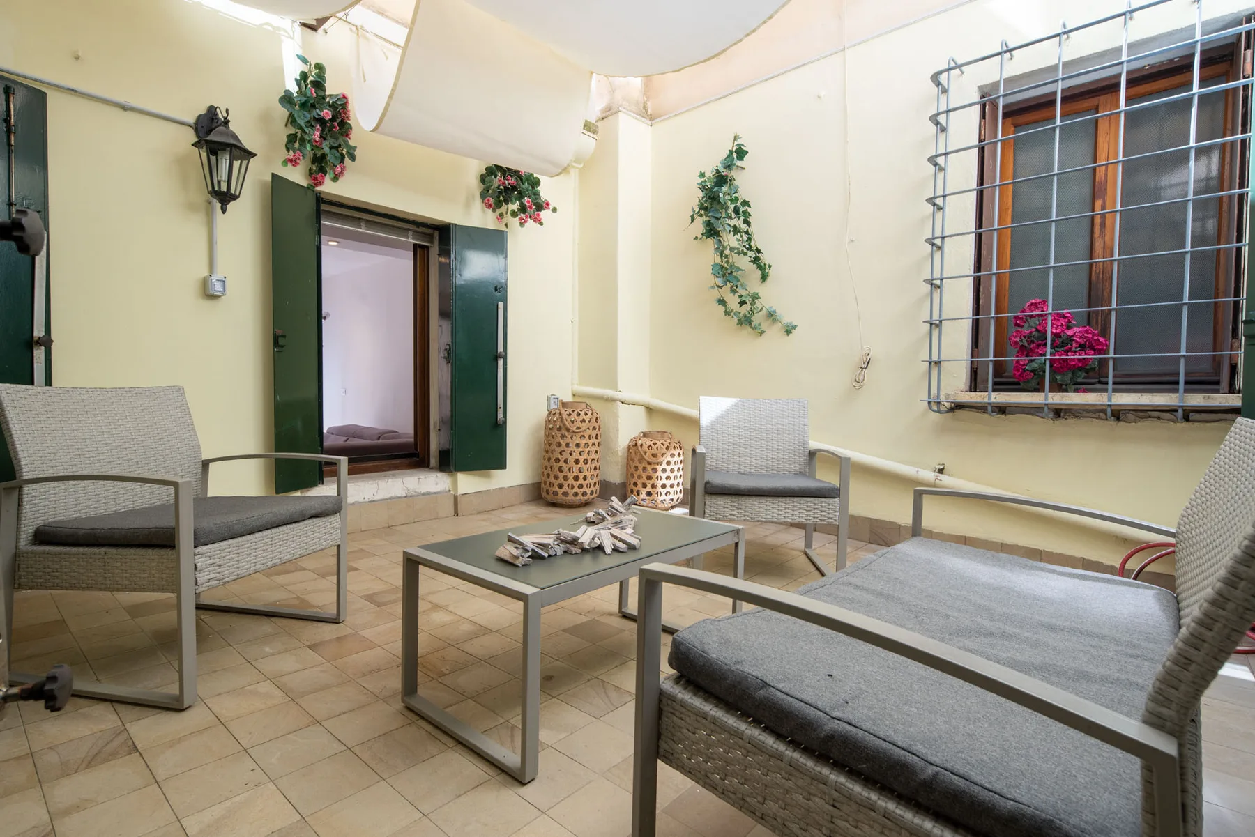 A tiled patio with seating around a low table and an open doorway.