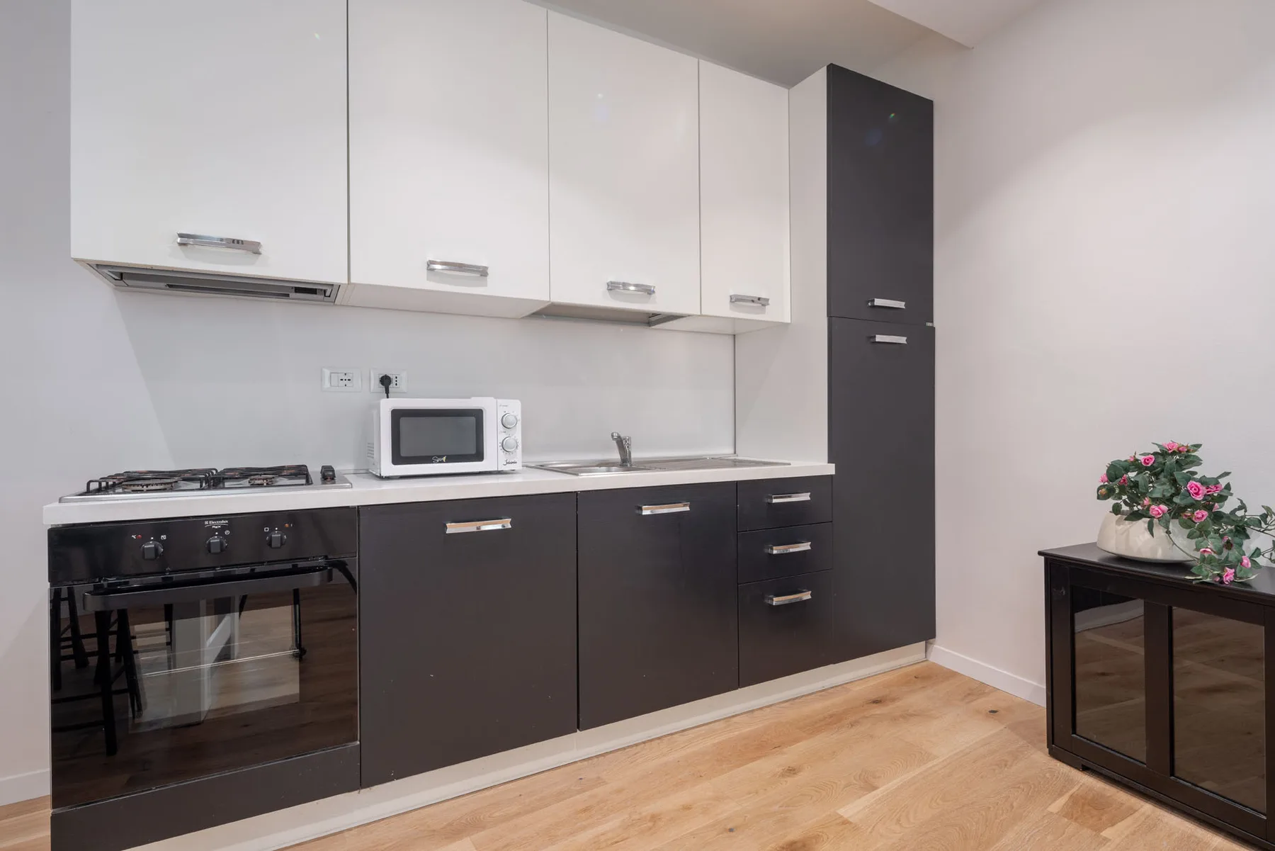 A modern kitchen with dark lower cabinets, white upper cabinets, and a countertop.