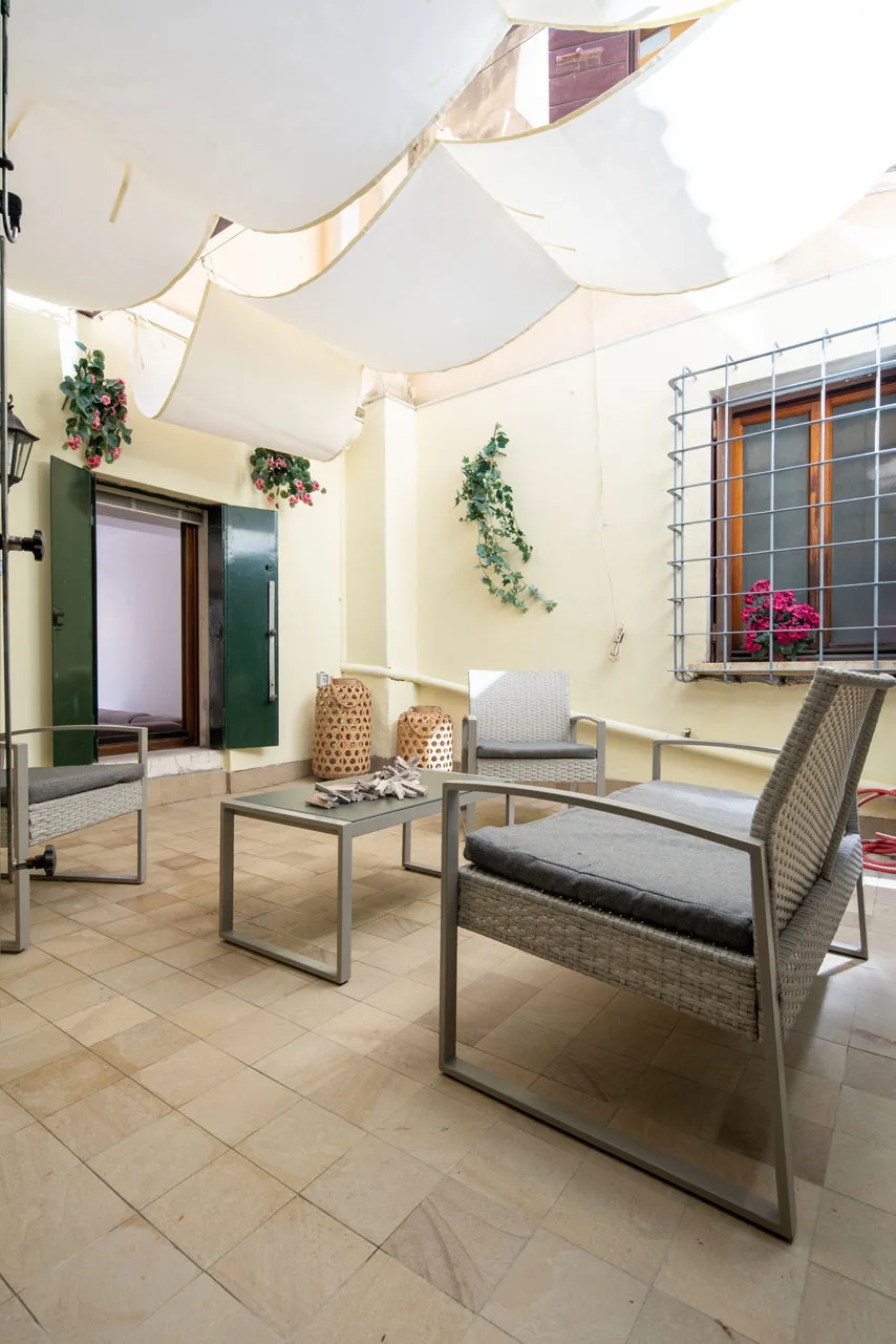 A covered patio with a low table and cushioned seating.