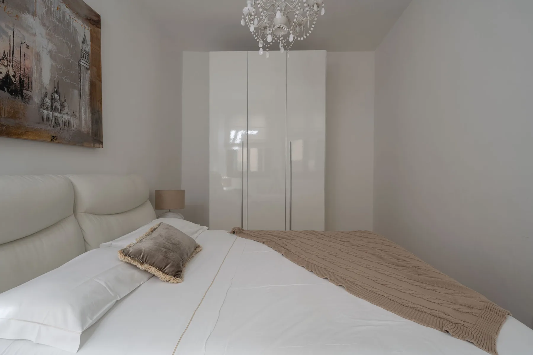 A bedroom with a large bed and a white wardrobe.