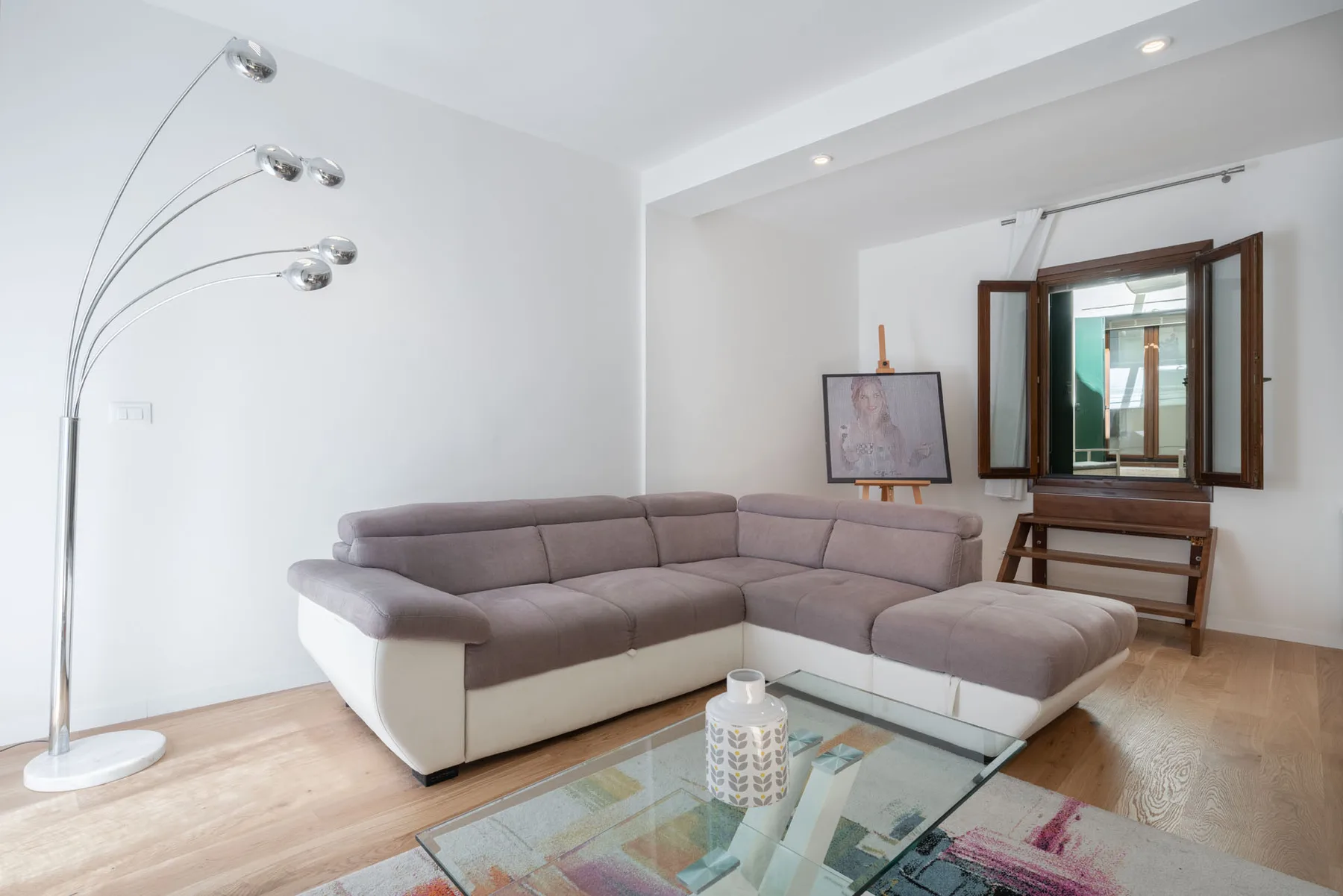 A bright living room with sectional seating and an open window.