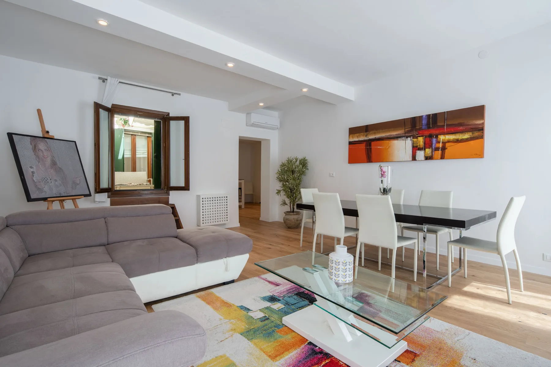 A bright living and dining area with seating, a glass coffee table, and a dining table.