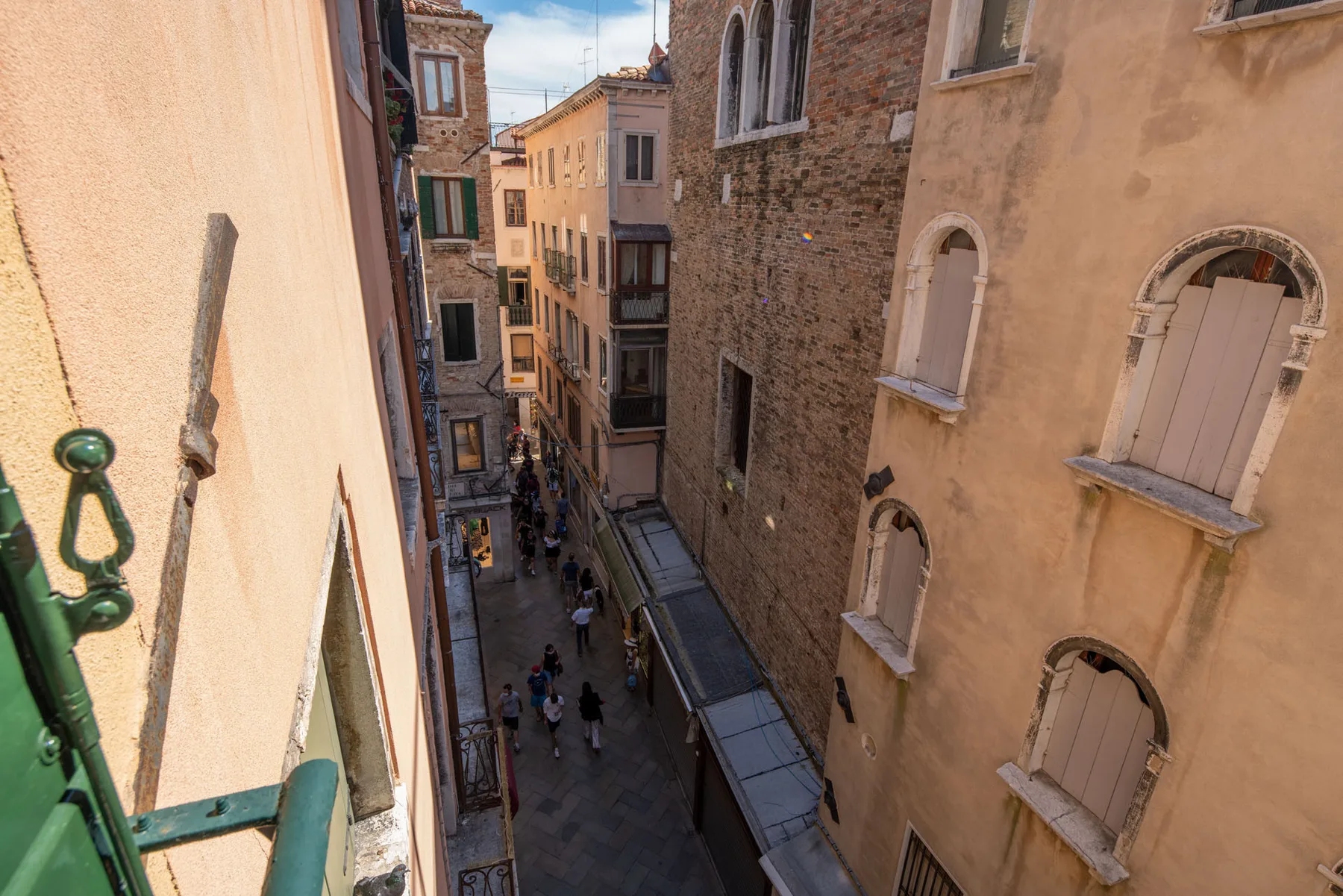 A narrow street runs between tall historic buildings, with pedestrians below.