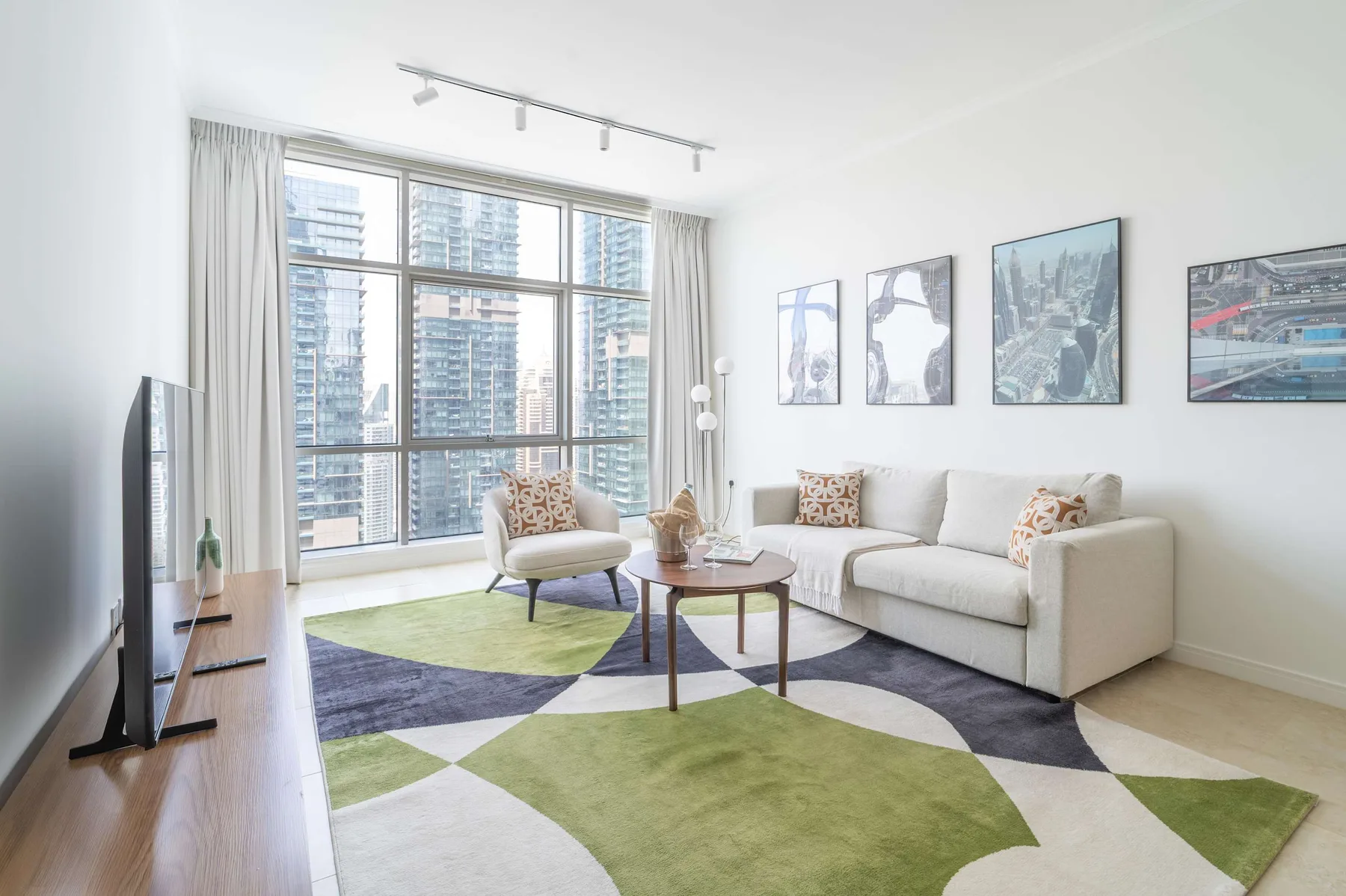 Una sala luminosa con sofá, sillón y grandes ventanas con vistas a la ciudad.