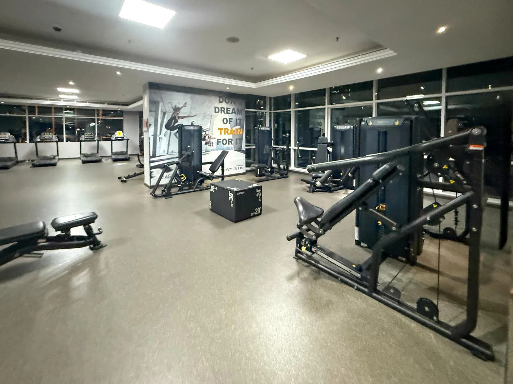 Un gimnasio con máquinas de ejercicio y equipo distribuido por la sala.