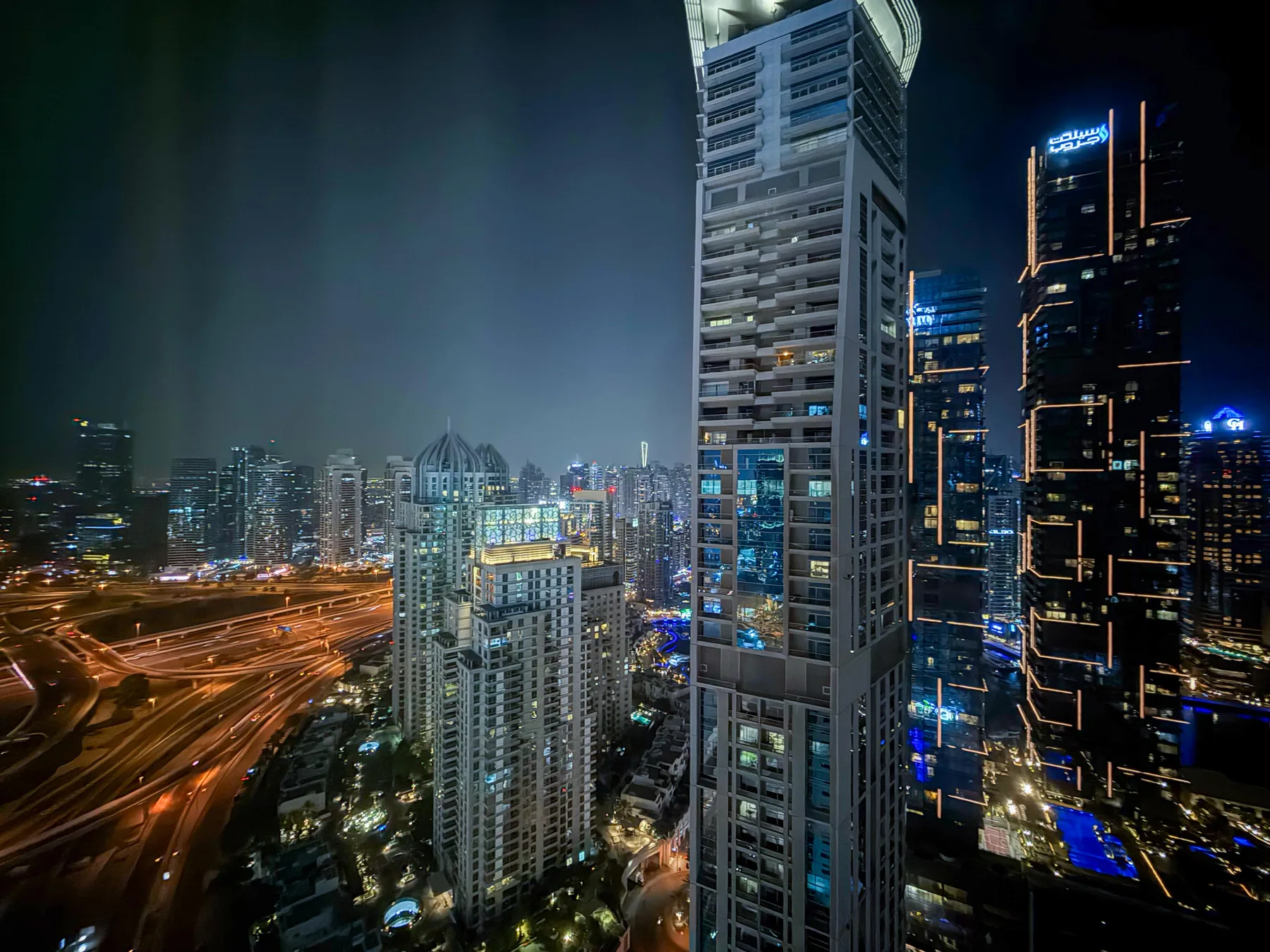 Un horizonte urbano nocturno con edificios altos iluminados y carreteras.