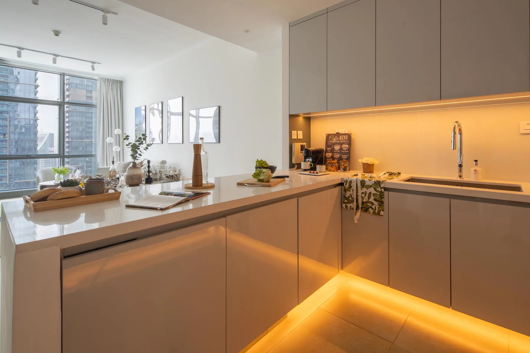 Una cocina moderna con una isla larga, asientos en la barra y ventanales.