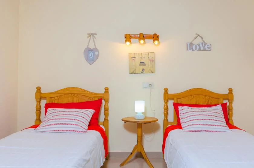 A bedroom with two beds, a small table, and wall decorations.